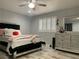 Bedroom with laminated wood-style flooring, ceiling fan, white plantation shutters, and mirrored furniture at 6441 Brushwood Ln, Las Vegas, NV 89107
