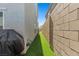 Narrow side yard with artificial turf between the home and brick wall at 6964 Caldera St, Las Vegas, NV 89149