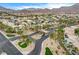 This aerial view shows a desert community entrance featuring lush palm trees and desert landscaping at 703 Jane Eyre Pl, Henderson, NV 89002