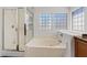 Bright bathroom featuring a glass shower, jetted tub, and glass block windows at 741 Wildwood Beach Ave, Henderson, NV 89052
