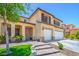 View of a beige two-story home with a well-manicured lawn, neutral accents and a double garage at 7619 Comanche Canyon Ave, Las Vegas, NV 89113