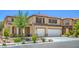 Front of beige two-story home featuring a well-manicured lawn, double garage and neutral accents at 7619 Comanche Canyon Ave, Las Vegas, NV 89113