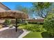 Landscaped backyard oasis featuring a tiki umbrella, patio, and lush green lawn at 7818 Brodie Castle Ct, Las Vegas, NV 89166