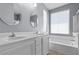 A well-lit bathroom featuring a double sink vanity, framed mirrors, and soaking tub with large window at 7818 Brodie Castle Ct, Las Vegas, NV 89166