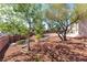 Lush backyard features mature trees and desert landscaping with mulched beds and brick retaining walls at 786 Craigmark Ct, Henderson, NV 89002