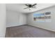 A cozy bedroom featuring a ceiling fan, window with security bars, and carpet floors at 809 Greenbrook St, Las Vegas, NV 89110