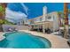 Backyard swimming pool with lush palm trees, privacy wall, and a covered patio with seating at 8953 Paige Rene Ct, Las Vegas, NV 89117