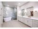 Modern bathroom with dual sinks, marble tile, soaking tub, and glass-enclosed shower at 9220 Pitching Wedge Dr, Las Vegas, NV 89134