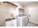 Clean laundry room with a modern sink, shelving, and updated washer and dryer units at 9220 Pitching Wedge Dr, Las Vegas, NV 89134
