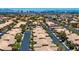 Aerial view of a community with tree-lined streets, light tiled roofs and a city skyline in the distance at 9357 Golden Timber Ln, Las Vegas, NV 89117