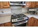 Close up of kitchen features including a stainless steel oven and stovetop with dark burners and light countertops at 9357 Golden Timber Ln, Las Vegas, NV 89117