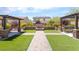 Landscaped backyard featuring artificial grass, brick pavers, a stone fire pit, and covered seating areas at , Las Vegas, NV 89149