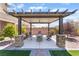 Cozy outdoor dining area with a stone firepit, seating, and a covered pergola at , Las Vegas, NV 89149