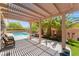 Inviting backyard patio shaded by a pergola with seating area, palm trees, and a view of the sparkling pool at 10331 Rio De Thule Ln, Las Vegas, NV 89135