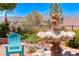 Close up of backyard showing fountain and landscaping, Adirondack chair and mountains in background at 1641 Rockcrest Hills Ave, Henderson, NV 89052