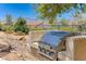 Built-in stainless steel outdoor grill with stone surround in a landscaped yard at 1641 Rockcrest Hills Ave, Henderson, NV 89052