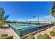 Tennis courts surrounded by a green fence, bushes and trees with a clear blue sky in the background at 1641 Rockcrest Hills Ave, Henderson, NV 89052