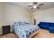 Comfortable bedroom with a soft carpet, ceiling fan, a bed with blue sheets, and a blue couch at 1717 Jake Andrew Ave, North Las Vegas, NV 89086