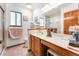 Well-lit bathroom featuring a large mirror, wooden cabinets, and a glass-enclosed shower at 1723 Candice St, Las Vegas, NV 89156