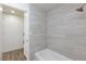 Updated bathroom featuring sleek, gray tiling, a shower-tub combo and updated flooring at 2112 Los Altos St, Las Vegas, NV 89102