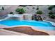 Backyard pool featuring a rock waterfall, fire pit, and manicured landscaping, perfect for relaxation at 2197 Big Bar Dr, Henderson, NV 89052
