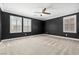 Spacious bedroom with neutral carpet, ceiling fan, and bright windows with white shutters at 2385 Via Firenze, Henderson, NV 89044