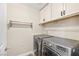Bright laundry room with stainless steel washer and dryer and white storage cabinets above at 2385 Via Firenze, Henderson, NV 89044