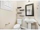 Stylish powder room with pedestal sink, decorative shelves, and modern fixtures at 2385 Via Firenze, Henderson, NV 89044