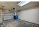 Spacious garage with modern door, concrete floor, overhead light, and two blue recycling bins at 2732 Heritage Ct, Las Vegas, NV 89121