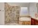 Tiled bathroom featuring a glass-enclosed shower, soaking tub, and vanity with decorative touches at 2779 Kindeace Ave, Henderson, NV 89044