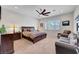 This well-lit bedroom has a ceiling fan, dark wood furniture, and cozy seating for relaxation at 2779 Kindeace Ave, Henderson, NV 89044