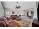 Open concept living room features ceiling fan, leather furniture, and view of kitchen at 2779 Kindeace Ave, Henderson, NV 89044