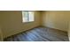 Bright bedroom featuring wood-look flooring and a window with security bars allowing natural light to fill the room at 3412 Mercury St # I, North Las Vegas, NV 89030