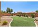 This backyard features an artificial lawn, mature shrubbery, and a brick perimeter wall at 3609 Kingfishers Catch Ave, North Las Vegas, NV 89084