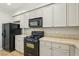 Close-up of kitchen featuring neutral cabinets and black appliances at 3609 Kingfishers Catch Ave, North Las Vegas, NV 89084