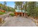 Charming log cabin-style home with a green roof, nestled amongst trees with a driveway and ample parking at 401 Alpine Way, Mount Charleston, NV 89124