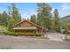 Charming log cabin-style home with a green roof, surrounded by lush greenery and mature trees at 401 Alpine Way, Mount Charleston, NV 89124