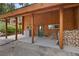 Covered porch with log beams provides access to the home, alongside a woodpile and convenient hot tub hookups at 401 Alpine Way, Mount Charleston, NV 89124