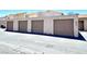 This image shows multiple garages with tan doors and textured walls under a blue sky at 5215 Gray Ln, Las Vegas, NV 89119