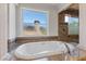 Luxurious bathroom features an oval soaking tub with granite countertop and backsplash at 73 Kittansett Loop, Henderson, NV 89052