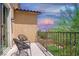 Relaxing balcony with seating and views of neighborhood landscaping under a colorful sky at 7733 Harthill Park Ave, Las Vegas, NV 89113
