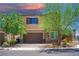 Two-story home featuring stone accents, a two-car garage, and a well-manicured front yard with mature trees at 7733 Harthill Park Ave, Las Vegas, NV 89113