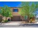 Two-story home featuring stone accents, a two-car garage, and a well-manicured front yard with mature trees at 7733 Harthill Park Ave, Las Vegas, NV 89113