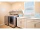 Functional laundry room with modern washer and dryer, counter space and storage cabinets at 7733 Harthill Park Ave, Las Vegas, NV 89113