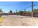 A backyard features a dirt area, a fence, foliage, and utility lines overhead at 805 E Carey Ave, North Las Vegas, NV 89030