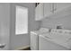 Bright laundry room with white washer, dryer, and upper cabinets at 9131 Grand Sunburst Ct, Las Vegas, NV 89149
