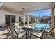 Inviting covered patio with seating area overlooks a stunning pool with a rock waterfall feature at 9612 Glengarry Dr, Las Vegas, NV 89129