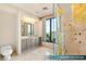 Primary bathroom features a glass shower, ample vanity space and storage, and a large window overlooking the city at 1 Hughes Center Dr # 903, Las Vegas, NV 89169