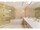 An elegant primary bathroom with double vanity, tile surround tub, and a glass enclosed shower at 1 Hughes Center Dr # 903, Las Vegas, NV 89169