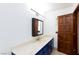 Bright bathroom with a spacious vanity, framed mirror, stylish lighting, and a wooden door on the right at 1050 Morgan Ln, Pahrump, NV 89060